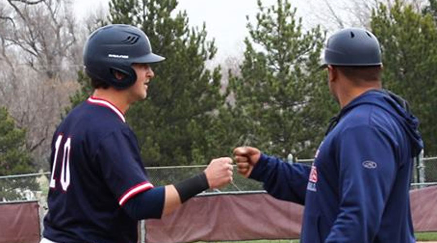 Ryan Moritz and third base coach Jamel Cervantez fist bump after Moritz's first triple of the season in Hutchinson's 6-1 win over Redlands on Tuesday at Hobart-Detter Field. (Bre Rogers/Blue Dragon Sports Information)